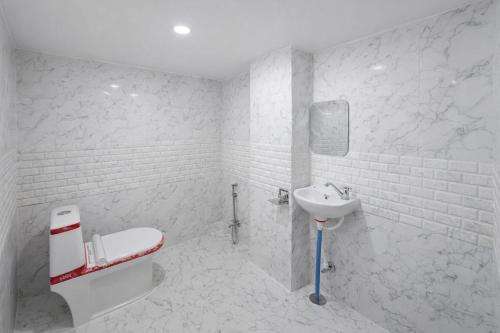 a white bathroom with a sink and a toilet at Hotel In Kashi in Varanasi