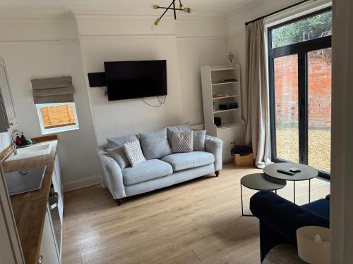 a living room with a couch and a tv at Freshly decorated apartment 10 mins from Cotswolds Child Friendly Great location with plenty of nearby free parking freestanding bath and outdoor private terrace area in Evesham