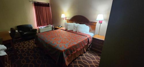 a hotel room with a bed and a chair at American Inn Evansville East in Evansville