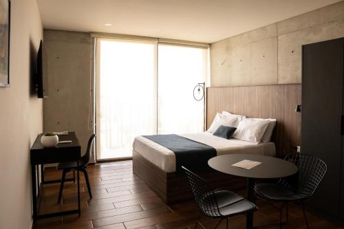 a hotel room with a bed and a table and a window at Lapso At Asís in Guadalajara