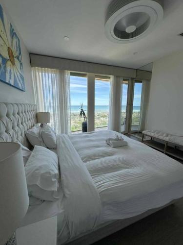 a large white bed in a bedroom with windows at Oceanfront Oasis in Grange