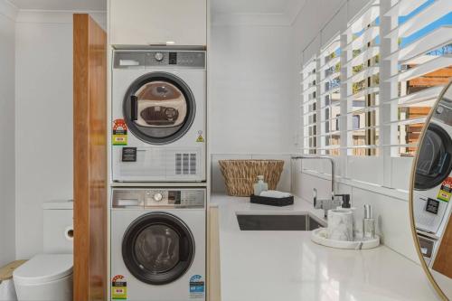 a laundry room with two washing machines and a toilet at Bunkers at Seven Mile in Seven Mile Beach