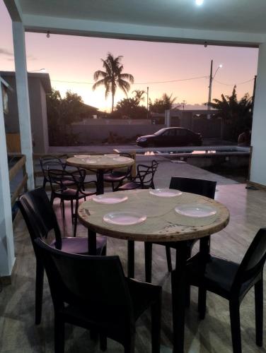 a group of tables and chairs with a sunset in the background at Casa Telhado Inclinado in Saquarema