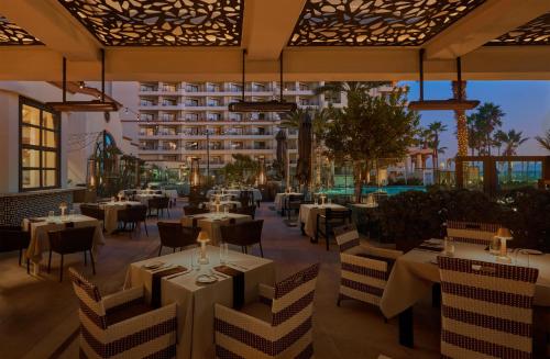 a restaurant with tables and chairs and a building at The Waterfront Beach Resort, A Hilton Hotel in Huntington Beach