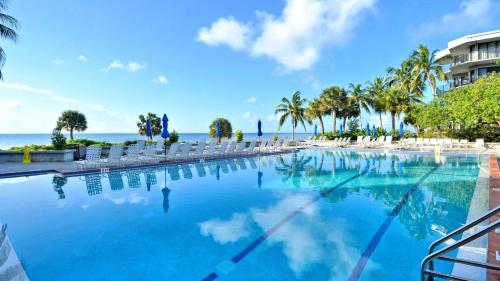 a large swimming pool with the ocean in the background at Atlantic Paradise by AvantStay Great Location w Balcony Outdoor Dining Shared Pool Hot Tub in Key West