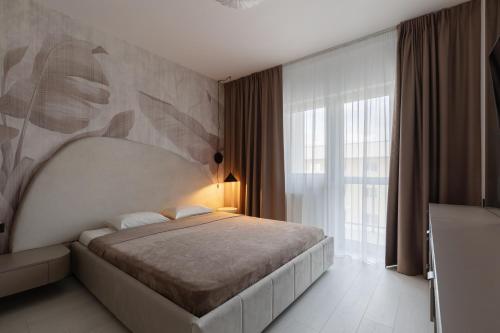 a bedroom with a bed and a large window at The Signature by D'or Selection in Bucharest