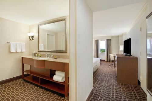 a hotel room with a bathroom with a sink and a mirror at Hilton Jackson in Jackson
