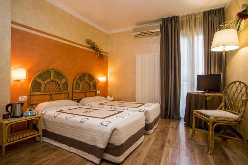 um quarto de hotel com duas camas e uma televisão em Hotel Le Pageot em Aosta