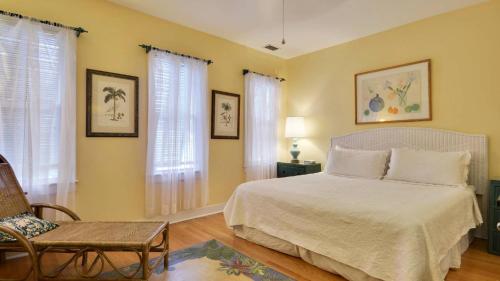 a bedroom with a bed and a chair and windows at Tropical Dreaming by AvantStay 4 BLKS to Beach Private Pool in Key West