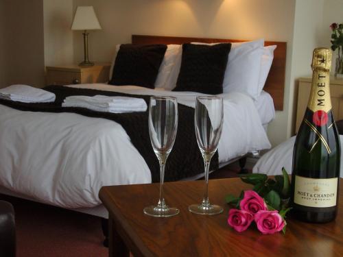 a bed with a bottle of champagne and two glasses on a table at Marine Lodge in Great Yarmouth