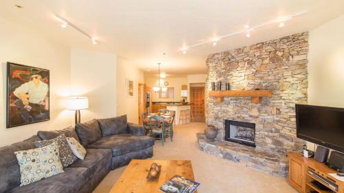 a living room with a couch and a stone fireplace at Westermere 311 - 2 by AvantStay Just Steps From Ski Area w Great Views in Telluride