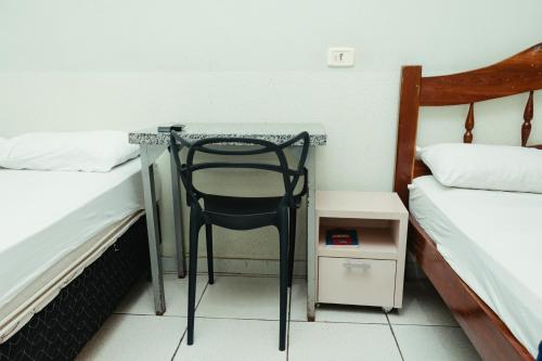 a desk with a chair in a room with two beds at Lagos Hotel in Itajubá