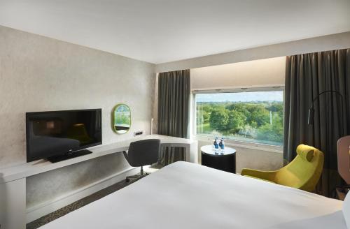 a hotel room with a bed and a large window at Hilton London Heathrow Airport in Hillingdon