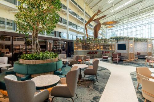 a lobby of a building with tables and chairs at Hilton London Heathrow Airport in Hillingdon
