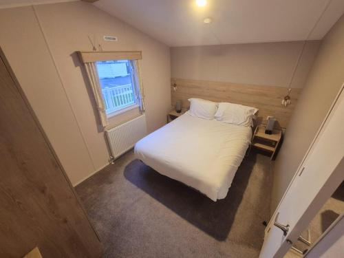 a small bedroom with a white bed and a window at Whitstable Hollington in Seasalter