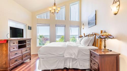 a bedroom with a bed and a tv and windows at Harborview Getaway by AvantStay in Langley