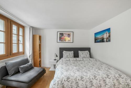 a white bedroom with a bed and a chair at Boël 3 studio in Geneva