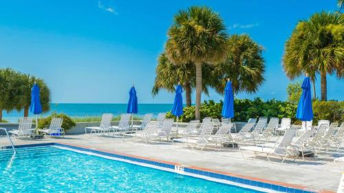 a pool with chairs and palm trees and the ocean at Beachfront 2BDR Condo Pool Hot Tub w Ocean Views Papaya Place by AvantStay in Key West