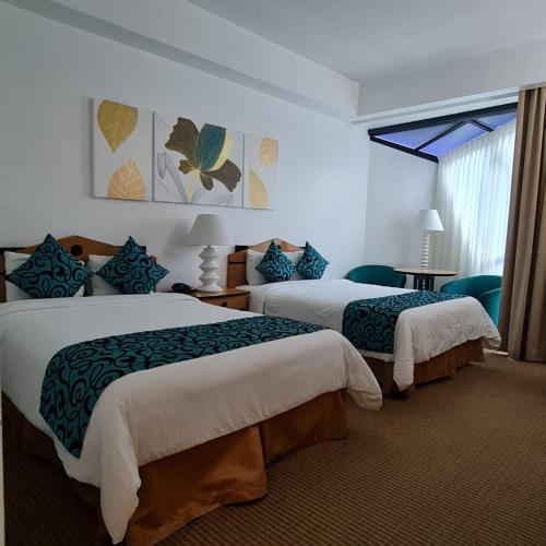 a hotel room with two beds and a window at Hotel Chacao Cumberland in Caracas