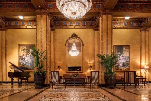 a lobby with a table and chairs and a chandelier at The Roosevelt Hotel New Orleans - Waldorf Astoria Hotels & Resorts in New Orleans
