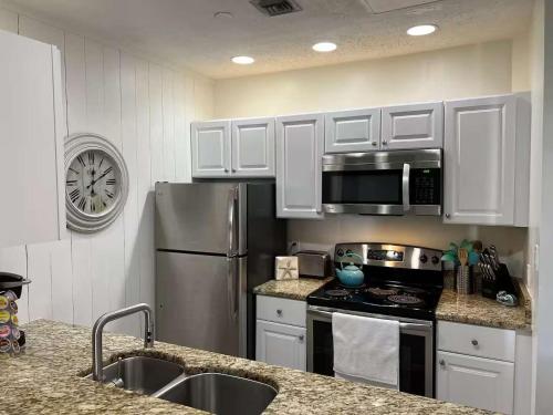 a kitchen with white cabinets and a stainless steel refrigerator at Charming condo with shared pool Gym and Tennis in Destin
