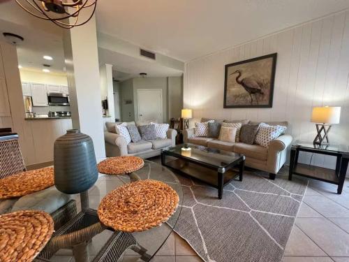 a living room with couches and tables and a kitchen at Charming condo with shared pool Gym and Tennis in Destin