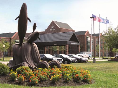 a statue in a park with flowers in front of a building at Hilton Mystic in Mystic