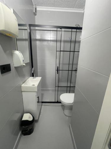 a white bathroom with a toilet and a shower at Başkent Otel in Mudanya