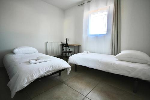 two beds in a room with a window and a table at Villa avec vue - terrasse - parking in Irigny