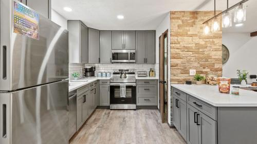 a kitchen with stainless steel appliances and gray cabinets at The Bears Den by AvantStay Prime Location Renovated w Movie Game Room in Crescent Lake