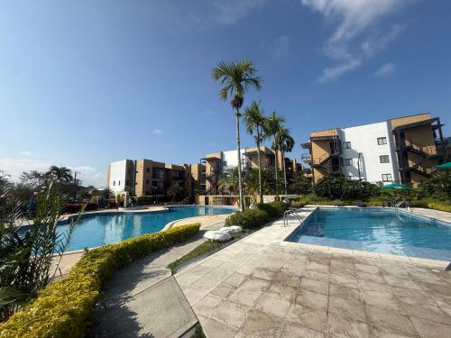 a resort with two pools and palm trees and buildings at Apartasol 102c Tebaida Quindio in La Tebaida