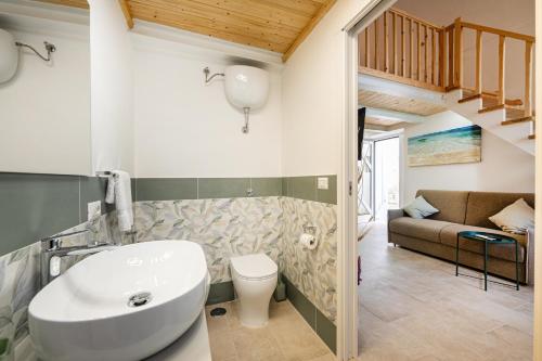a bathroom with a sink and a toilet and a couch at Respiro di Chiaia in Procida