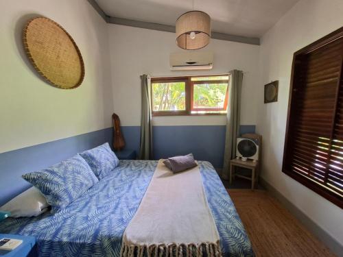 a bedroom with a bed with blue sheets and a window at Maison avec bungalow Ylang in Uturoa
