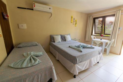 a bedroom with two beds and a table and a window at Albacora Eco Residence in Imbassai