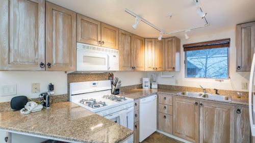 a kitchen with wooden cabinets and white appliances at Double Diamond 23 by AvantStay Close to Town The Slopes in Telluride