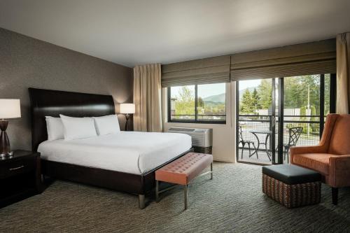 a bedroom with a bed and a chair and a balcony at Hilton Garden Inn Seattle/Issaquah in Issaquah