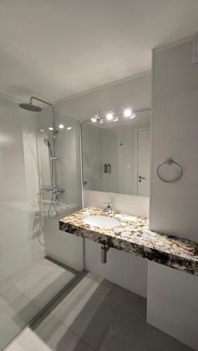 a white bathroom with a sink and a shower at Hotel Raices del Arapey in Termas del Arapey