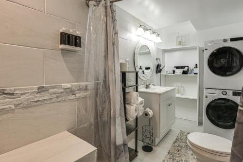 a bathroom with a shower and a sink and a washing machine at Oasis Hideaway Apt w/ Rainforest Shower! in Baltimore