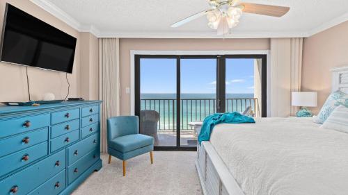 a bedroom with a bed and a blue dresser with a television at Beachfront Breeze by AvantStay in Panama City Beach