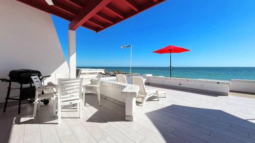 a patio with a table and chairs and an umbrella at Charming & Cozy Beachfront Condo Las Olas I 19 in Puerto Peñasco