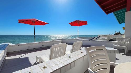 a patio with a table and chairs and the ocean at Charming & Cozy Beachfront Condo Las Olas I 19 in Puerto Peñasco