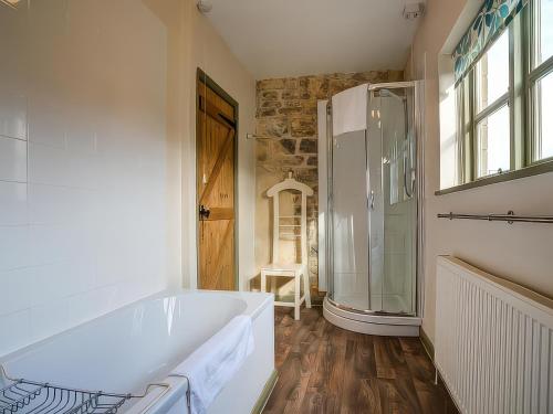 a bathroom with a tub and a glass shower at Elm View in Chipping Campden