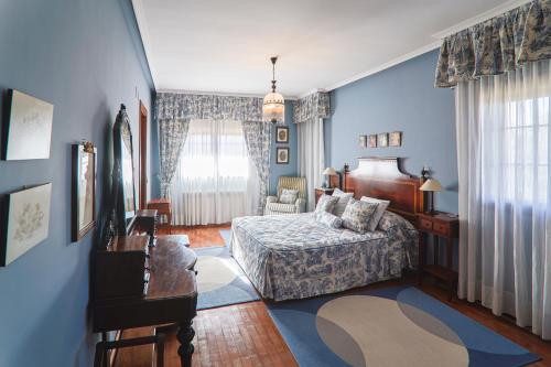 a bedroom with blue walls and a bed and a couch at Montesión 71 - Casa con piscina & jardín, al lado de Puy du Fou in Toledo