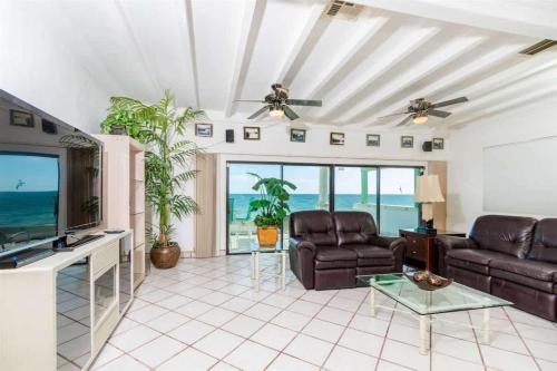 a living room with couches and a television and the ocean at Comfortable Beachfront Condo Las Olas II 1 in Puerto Peñasco