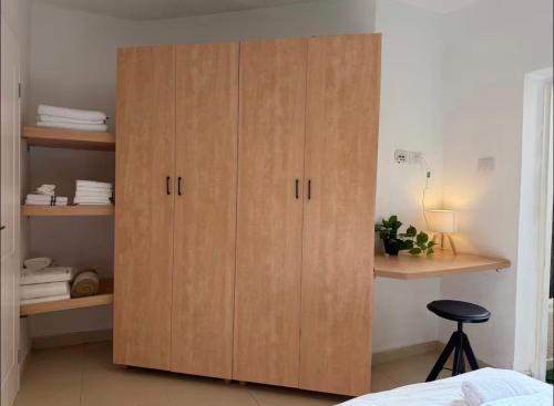 Ein großer Holzschrank im Schlafzimmer mit einem Hocker in der Unterkunft Green spot in Be’er Scheva