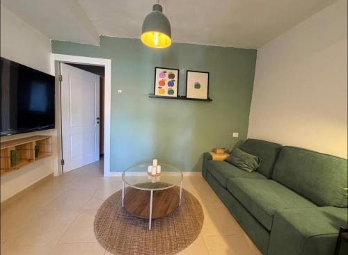 ein Wohnzimmer mit einer grünen Couch und einem Glastisch in der Unterkunft Green spot in Be’er Scheva