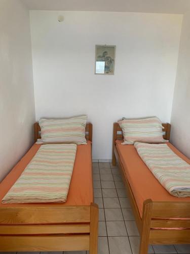 two beds sitting next to each other in a room at Robinzonska kuća uz more in Tkon
