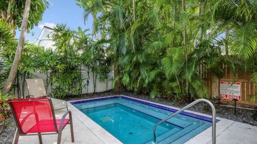 a swimming pool with a red chair and a red chair next to at Paradise Place by AvantStay Key West Old Town Condo w Shared Pool in Key West