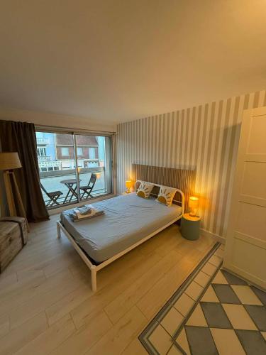 a bedroom with a bed and a large window at Studio Ti’Sable 50m de la plage in Fort-Mahon-Plage