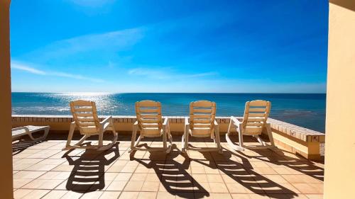 three chairs sitting on a balcony overlooking the ocean at Charming 3-Bedroom Beachfront Home Bahia Delfin in Las Conchas